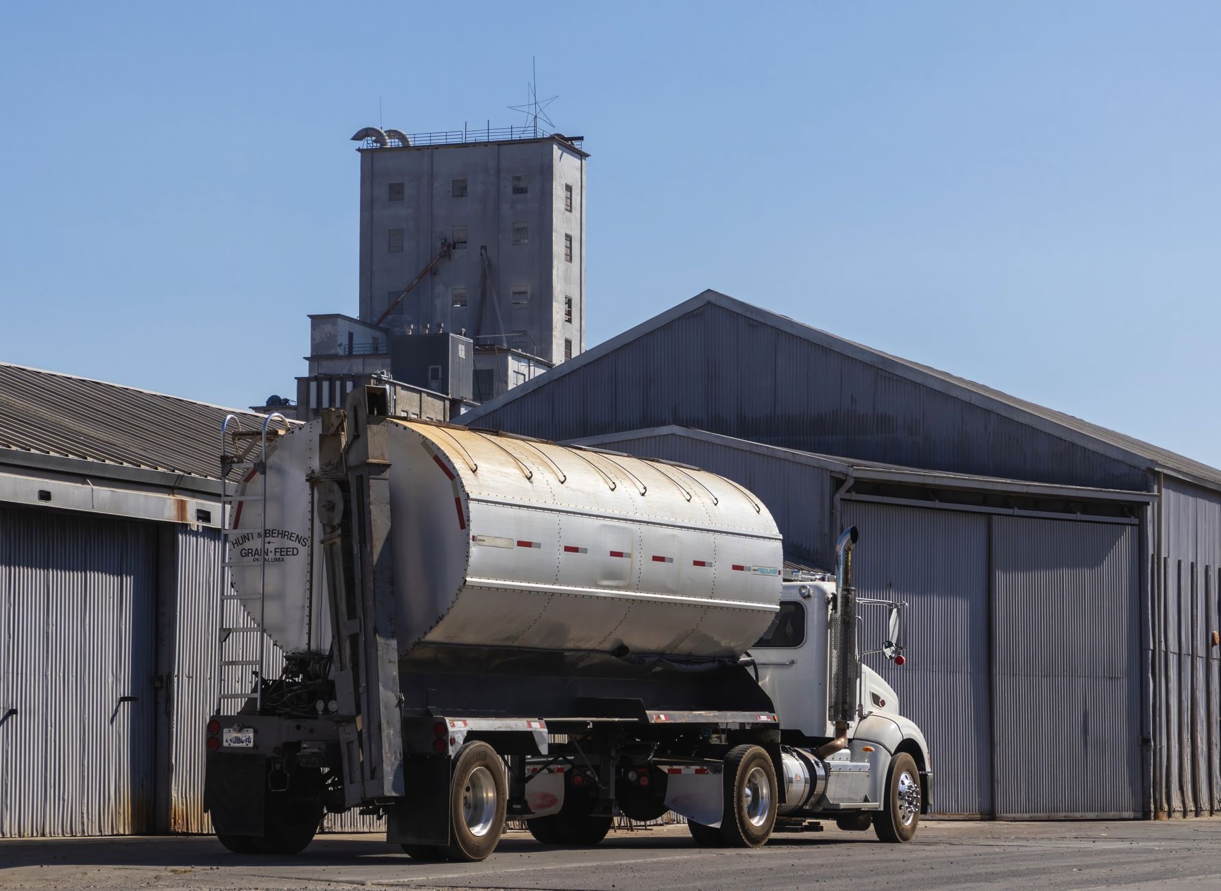 Camion-citerne de livraison de fioul domestique garé devant un silo agricole