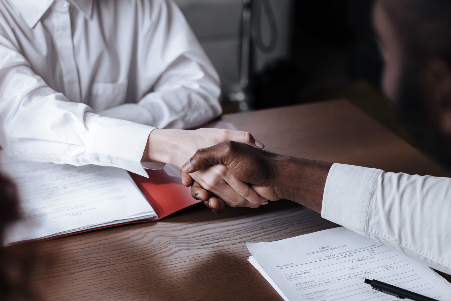 Poignée de main entre deux personnes en tenue professionnelle, au-dessus d'un document