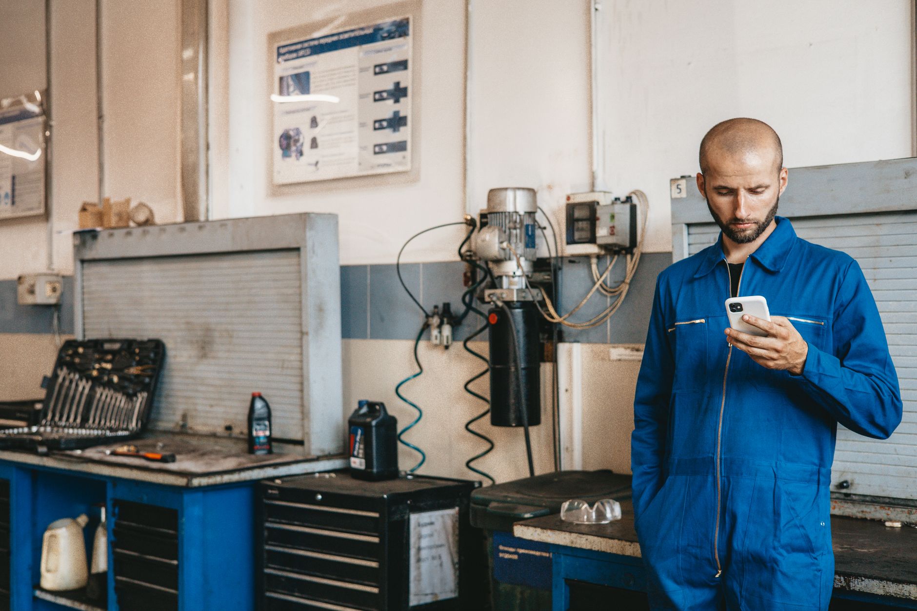 mécanicien en bleu de travail consultant son téléphone dans son garage