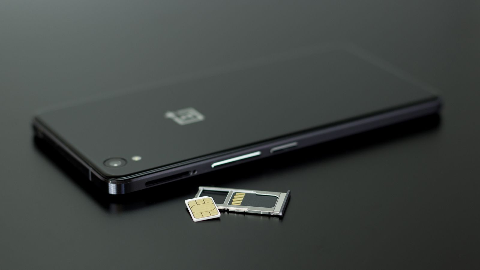 Carte SIM sortie de son tiroir à côté d'un smartphone, avant la portabilité du numéro mobile