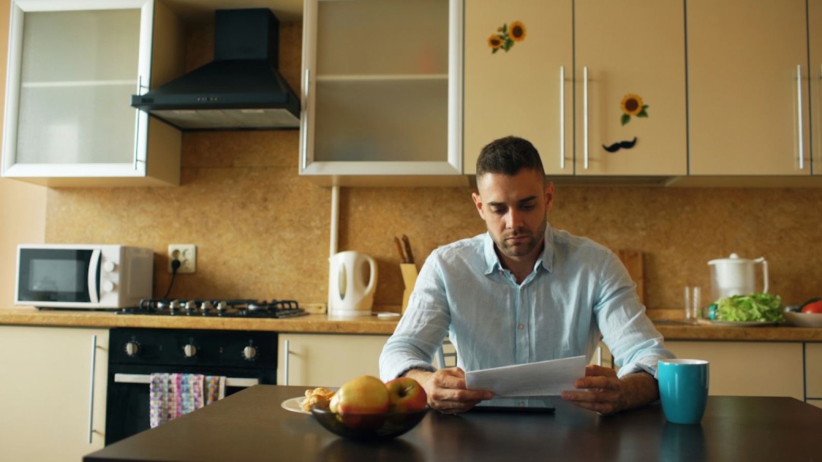 Un homme âgé consulte son smartphone devant des papiers administratifs posés sur une table
