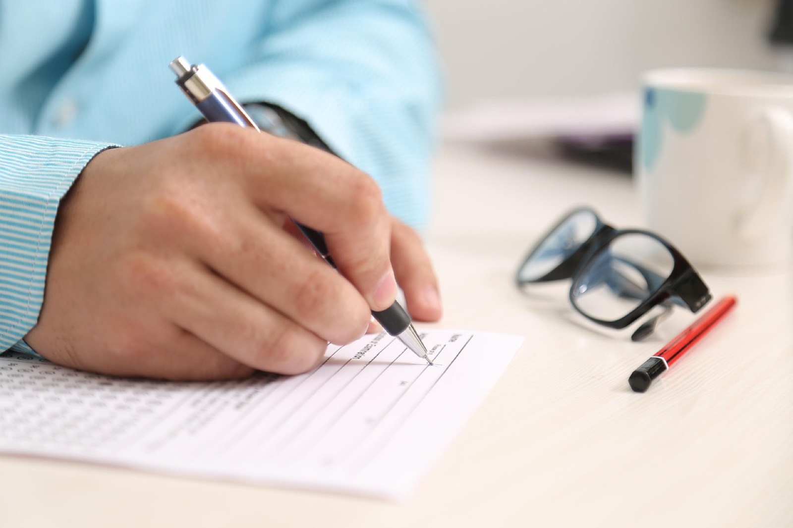 Main signant un document administratif sur un bureau