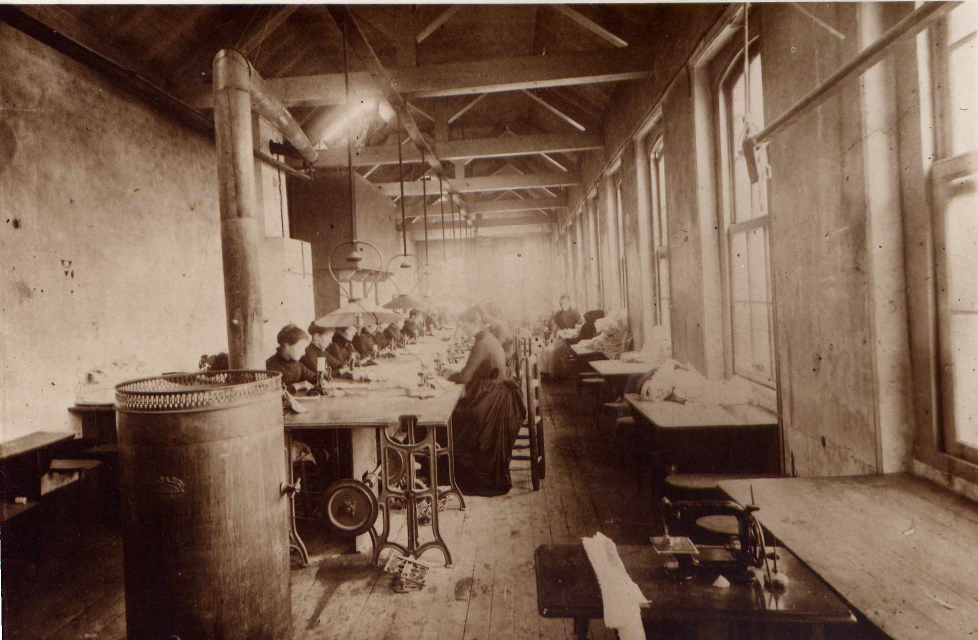 atelier de confection de chemises en 1888, ouvrières alignées devant des machines à coudre dans une longue salle
