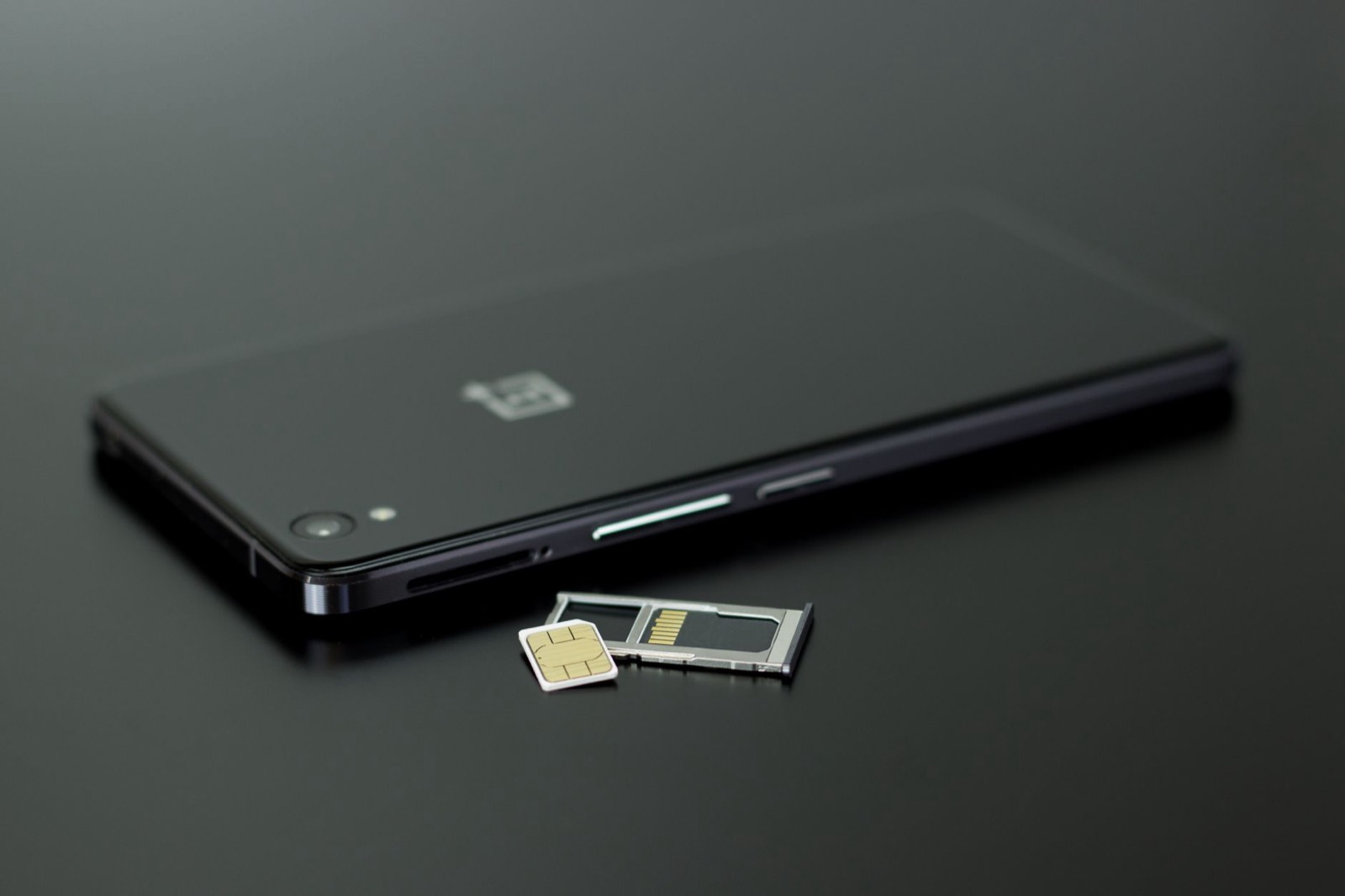 Main tenant une carte SIM à côté d'un smartphone