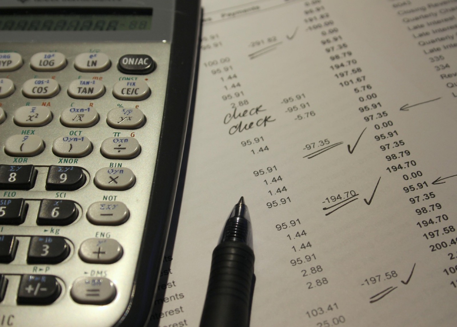 Calculatrice et stylo posés sur une facture papier pour vérifier le total avant l'envoi